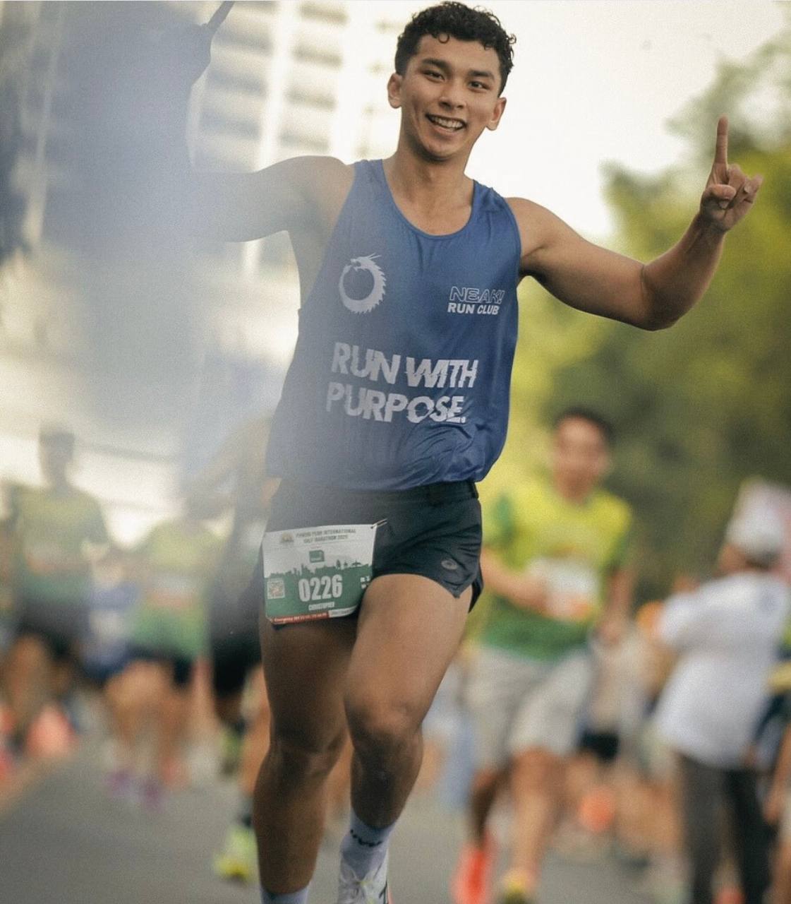 Christopher Chea smiling mid-race in the NEAK Run with Purpose singlet